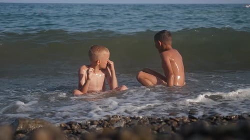 Children Have Fun on the Beach with Sea Waves Boys Splash in the Waves