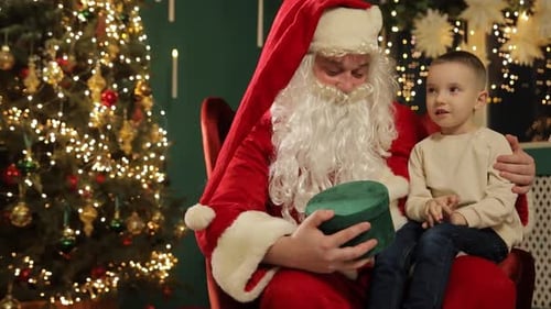 Boy Sits with Santa Claus with Christmas Present