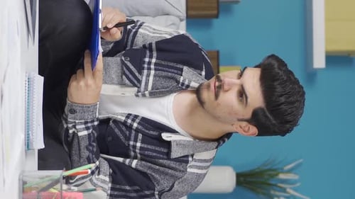 Vertical Video of Home office worker taking notes while looking at computer.