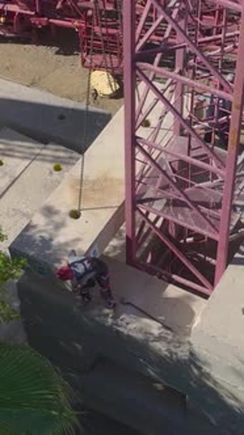 Vertical Video Construction Workers Building A Tower Crane OnSite Captured Aerially With Focus On