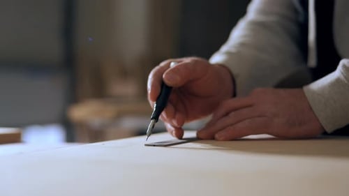 Carpenter Measuring and Marking Wooden Board with Ruler and Pencil During Woodworking Preparation in