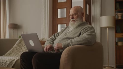 Senior Man Using Laptop Computer in Armchair