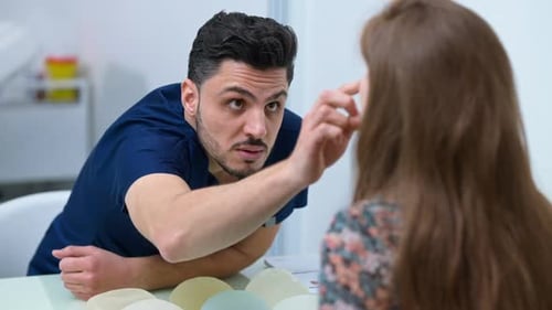 Concentrated Middle Eastern Plastic Surgeon Examining Face of Caucasian Woman Talking
