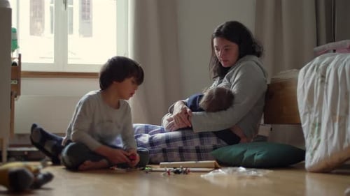 Mother and Children Relaxing, Playing on Floor Indoors