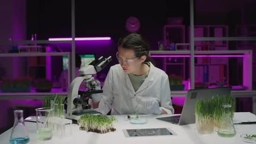 Asian Botanist Performing Microscopic Analysis on Plant in Laboratory