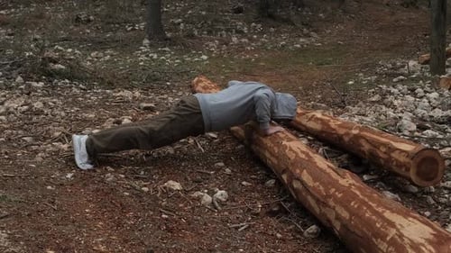 Man Doing Pushups on Logs in Woodland Area