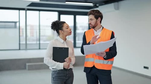 Architect and Investor Discuss Blueprints in Empty Office Space