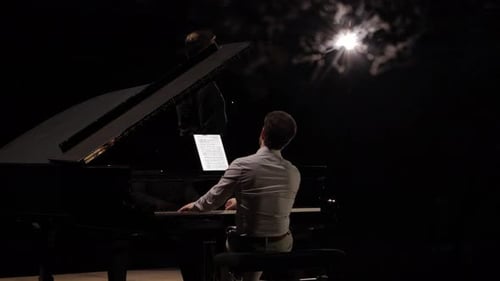 Pianist Playing Grand Piano on Stage at Night