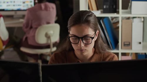 Mujer joven que trabaja en monitores duales en un entorno de oficina moderno