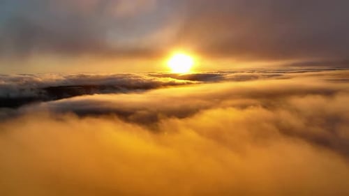 Sunset over the clouds, beautiful aerial view of rolling clouds and orange sun