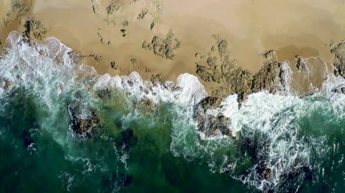 Aerial top view of waves break on rocks. Aerial drone top down view bird eye view of sea blue waves