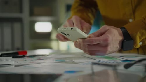 Analysis and analytics. An office worker holds a modern smartphone in his hands while in modern