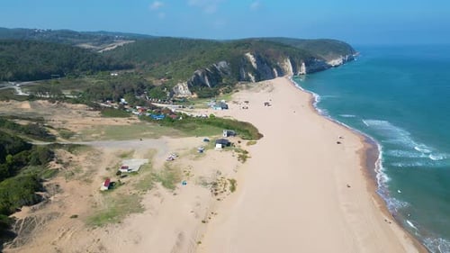 An Aerial View of Ocean Waves Breaking Gently Along a Lush Green Lined Beach