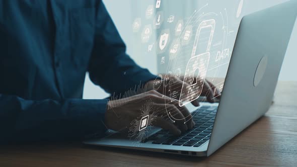 Professional working on laptop with cybersecurity graphics visualizing ...
