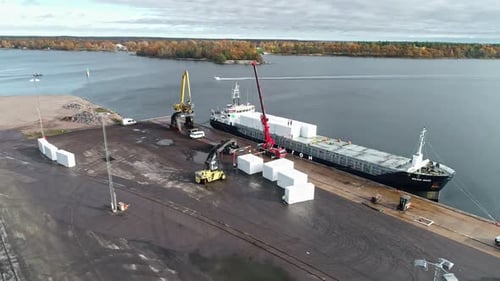 Luftaufnahme eines Industriekrans beim Laden von Waren auf ein Containerschiff im Hafen