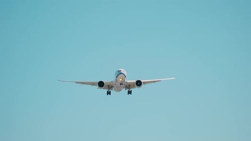 Plane Flying Over the Head Landing at Airport with Barbed Wire on Net Fence at Sunny Bright Day Time