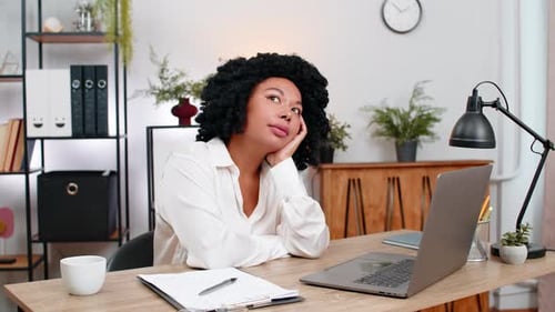 Woman Contemplates Work Sitting at Desk in Office
