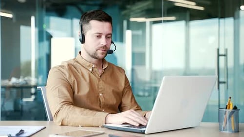 A corporate operator who works in customer support speaks on a video call using a laptop computer.