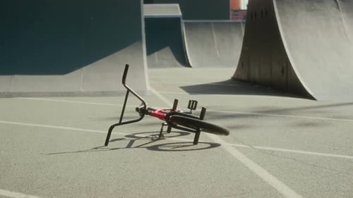 BMX Rider Jumping over Fallen Bike at Skate Park