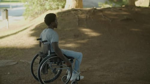 Young Black Man Riding His Wheelchair Outside on Summer Day