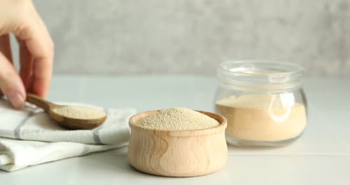 Dry yeast being poured into glass container indoors