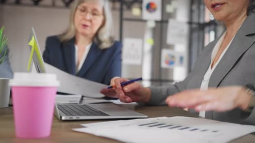 Une patronne et une femme chef de département discutant des rapports de vente dans le cadre de Boardroom Emancipation et