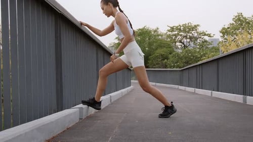 Young fitness woman in sportswear exercising in city park