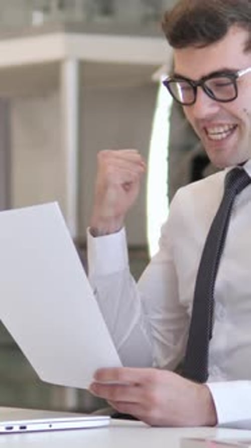 Excited Young Man Reads Good News in Office