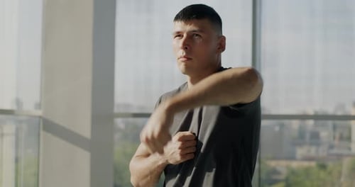Slow Motion Portrait of Man Doing Warmup Exercises for Arms Training in Light Modern Gym