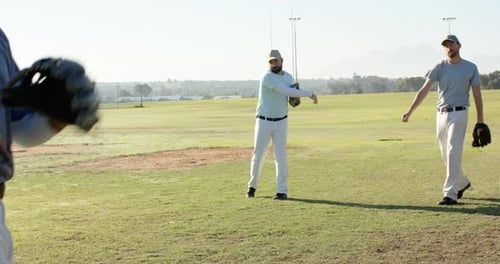 Male catcher stepping, fielding tossed baseball after underhand toss initiating drill on ball field