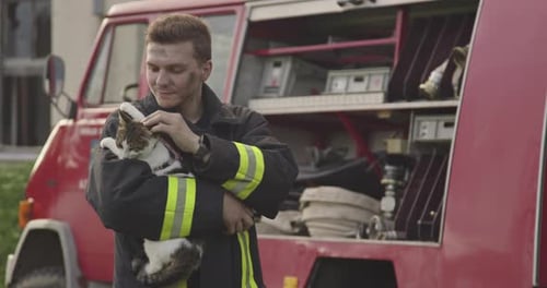 Portrait rapproché d'un pompier héroïque vêtu d'une combinaison de protection et tenant un chat sauvé dans ses bras