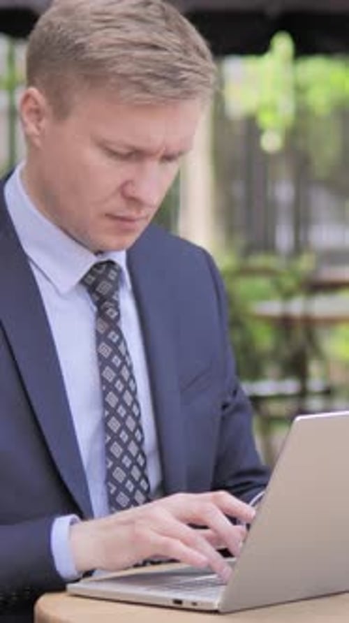 Businessman working on Laptop while Sitting in Outdoor Cafe, Vertical Video