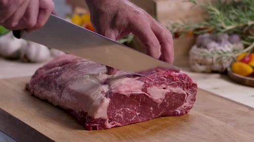 Chef Cutting Fresh Beef on Wood Cutting Board