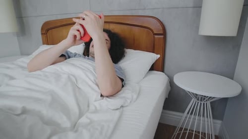 Man Waking Up, Reaching for Phone in Bedroom