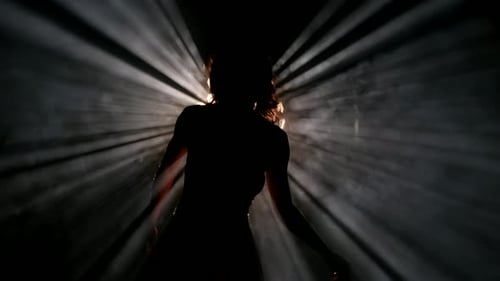 Verführerische Frau tanzt sinnlichen Tanz in der Dunkelheit Silhouette eines sexy Körpers vor hellem Licht