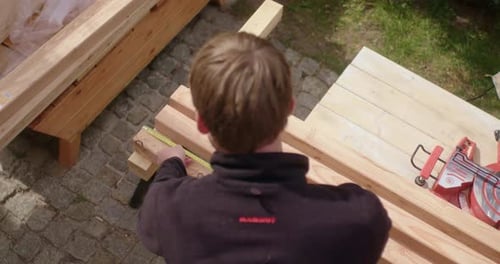 Man Measuring Planks for Woodworking Project Outdoors