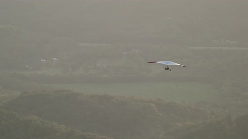 Hang Glider Flying Over Tree Covered Mountains