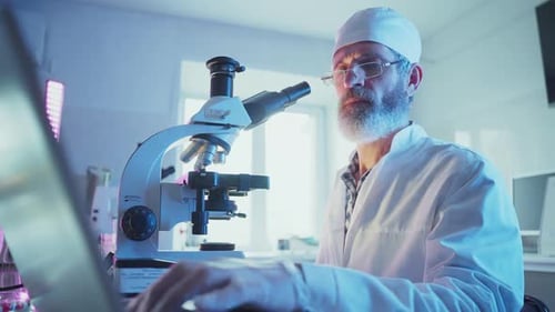 Wissenschaftler analysieren Proben mit Mikroskop und Laptop im Labor