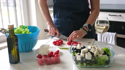 Woman Prepares Greek Salad in Bright Kitchen