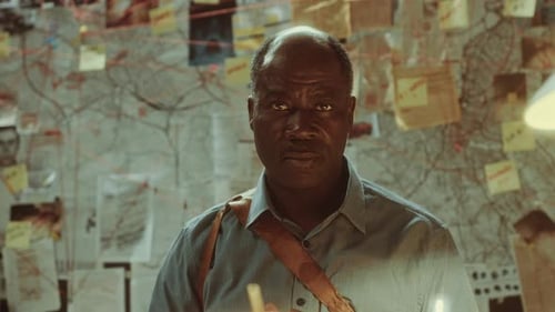 Portrait of Senior Black Detective Sitting at Desk in Office at Night