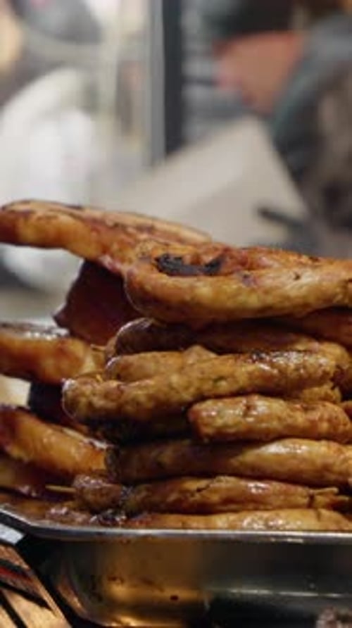 Vertical video Christmas market food stall displaying grilled sausages and pork ribs