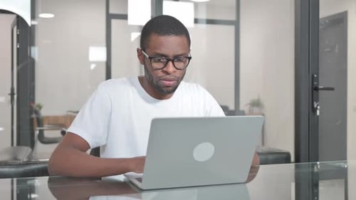 Young African Man Working on Laptop in Office