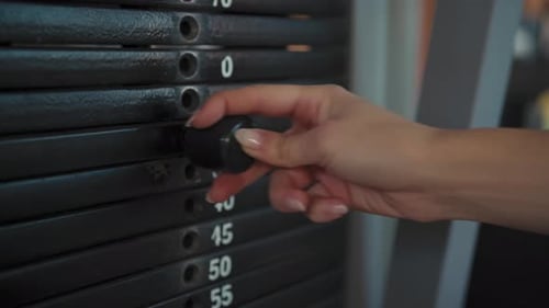 Frau wechselt die Hantelscheibe des Fitnessgeräts