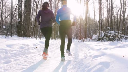 Winter Forest Young Man and Woman Running in the Morning