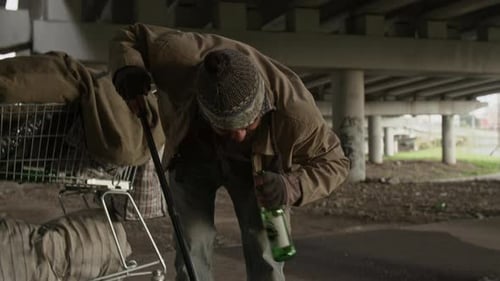 Man with Shopping Cart Picks up Bottle