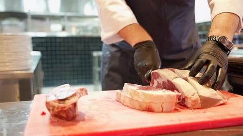 Close-up of a cook's cutting fatty steaks on a plastic cutting board, raw beef fillet (Cutting meat