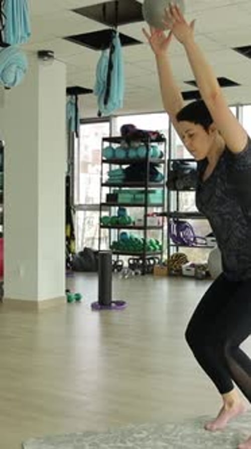 A Fit Woman Performs an Intense Workout Using a Medicine Ball in a Wellequipped Fitness Studio