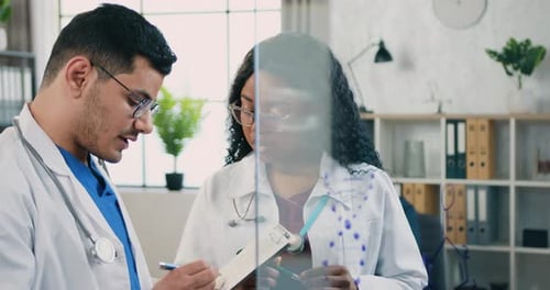 Woman doctor talking with her skilled bearded man colleague in medical office and discussing methods