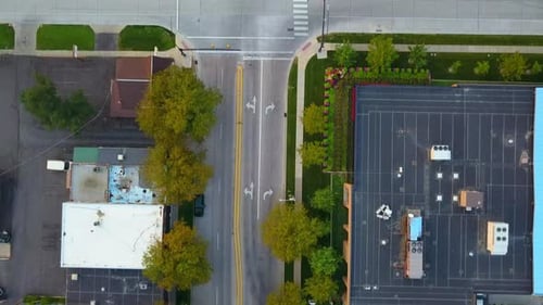 A drone shot passing over an intersection on a busy road. Multiple cars driving on it.