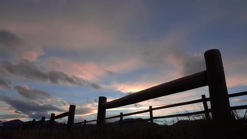 Time-Lapse Clouds Flowing over Rural Fence at Sunset